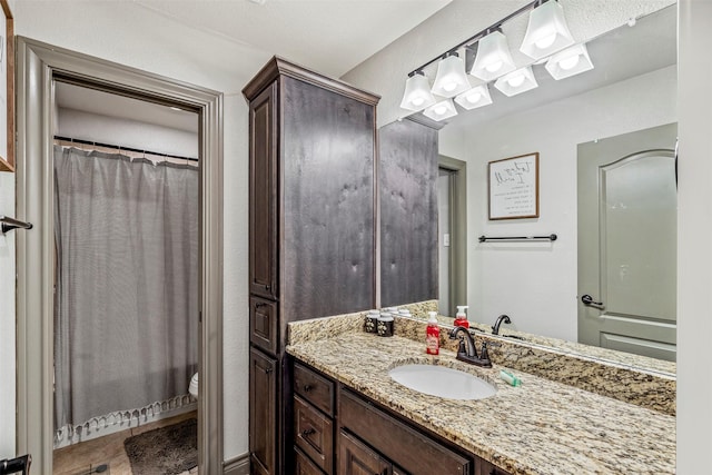 bathroom featuring a shower with shower curtain, vanity, and toilet