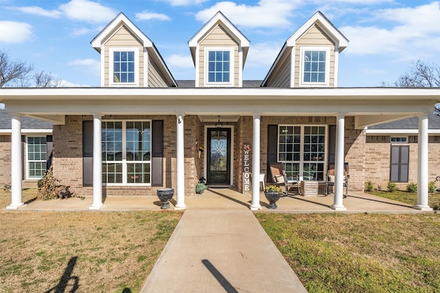 view of front facade with a front yard, covered porch, and brick siding