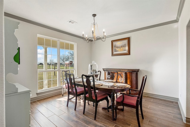 dining space with crown molding, a notable chandelier, visible vents, wood finished floors, and baseboards