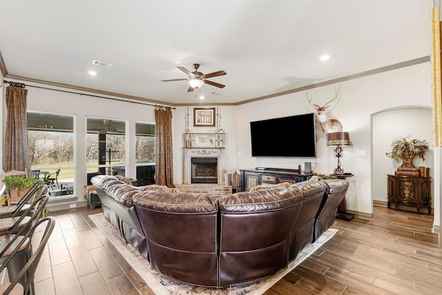 living area featuring ornamental molding, visible vents, ceiling fan, and wood finished floors