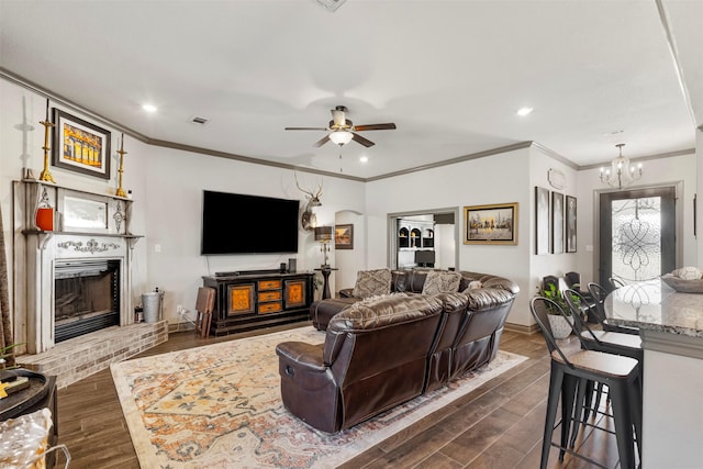 living area with dark wood-style flooring, a fireplace, visible vents, baseboards, and crown molding