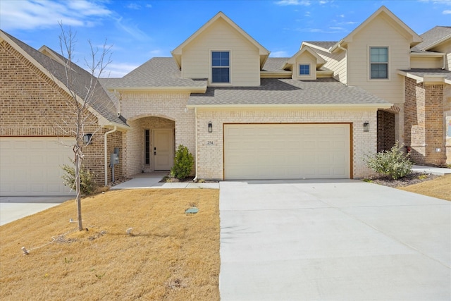 view of front facade featuring a garage, a shingled roof, concrete driveway, and brick siding