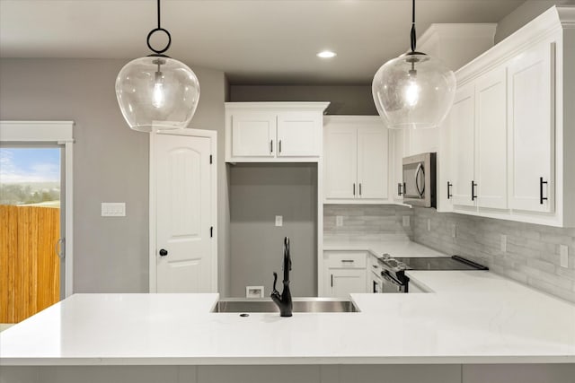 kitchen with appliances with stainless steel finishes, light countertops, a sink, and decorative backsplash