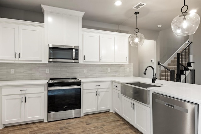 kitchen featuring stainless steel appliances, light wood-style floors, visible vents, and a sink