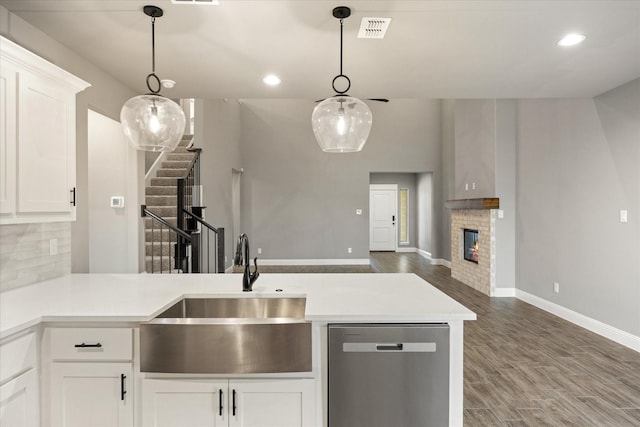 kitchen with visible vents, decorative backsplash, a sink, wood finished floors, and dishwasher