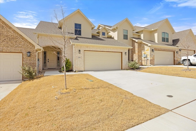 view of front of house with concrete driveway, brick siding, and roof with shingles