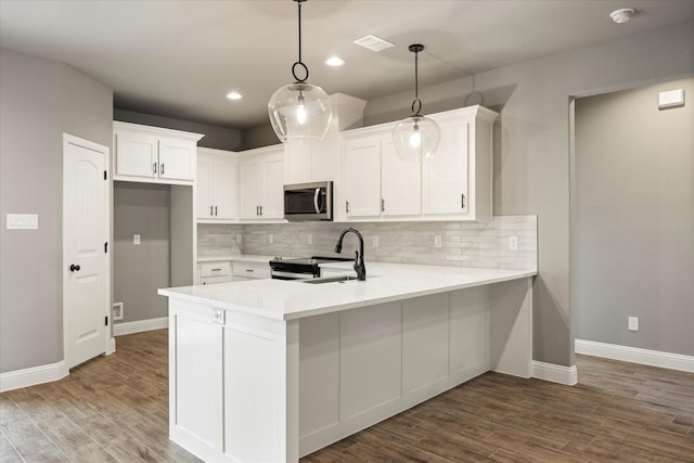 kitchen featuring visible vents, appliances with stainless steel finishes, wood finished floors, a peninsula, and a sink