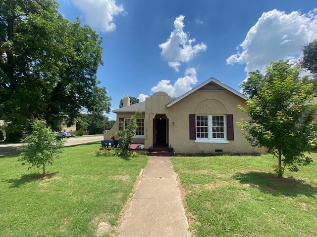 view of front of home featuring a chimney, a front yard, and stucco siding