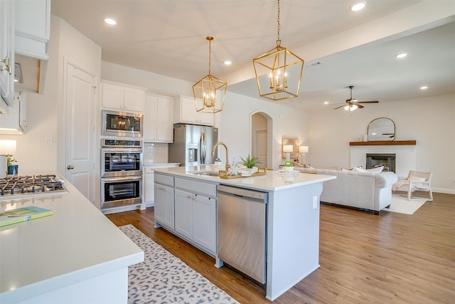 kitchen featuring light wood finished floors, a fireplace, stainless steel appliances, and light countertops