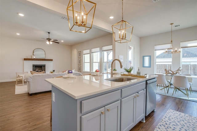 kitchen featuring visible vents, stainless steel dishwasher, a brick fireplace, a sink, and plenty of natural light