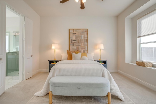 bedroom with a ceiling fan, light carpet, ensuite bath, and baseboards