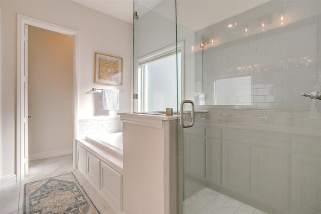 full bath featuring marble finish floor, a garden tub, a shower stall, and baseboards