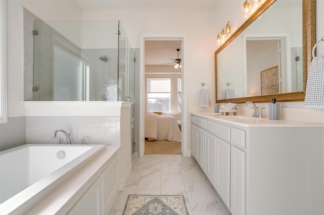 ensuite bathroom featuring a tub to relax in, marble finish floor, ceiling fan, vanity, and a shower stall