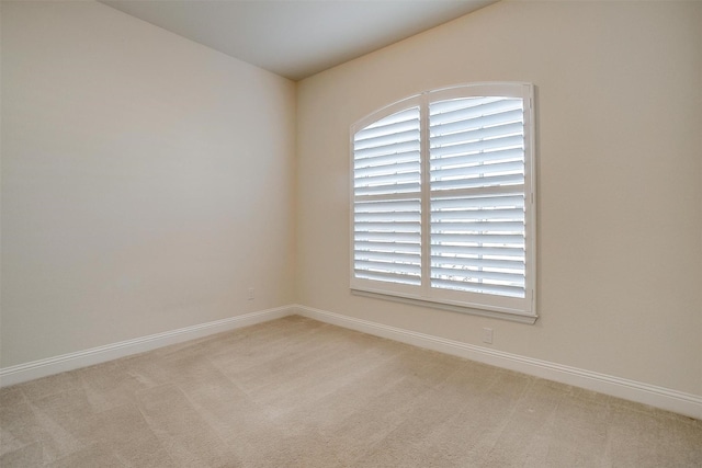 unfurnished room with light carpet and baseboards