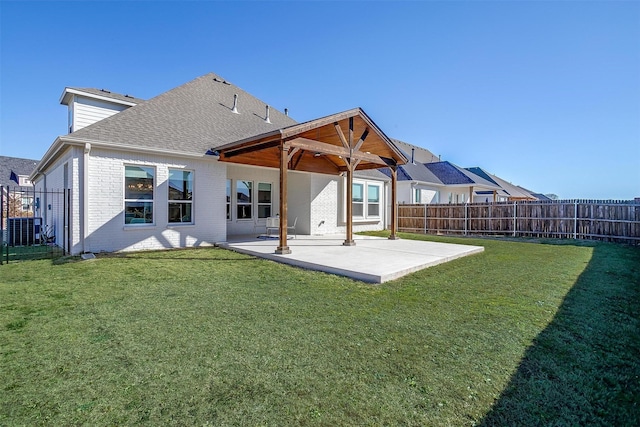 back of house featuring a yard, a patio, brick siding, and fence