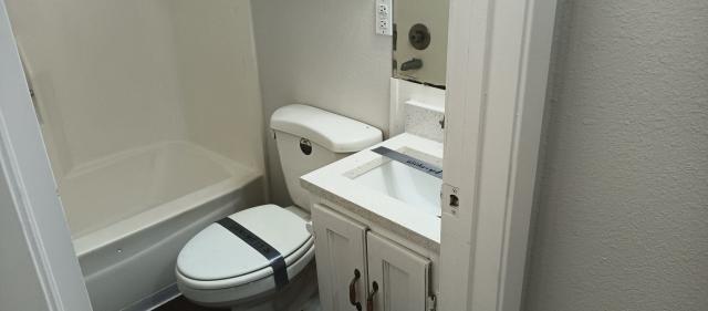 bathroom with a textured wall, vanity, and toilet