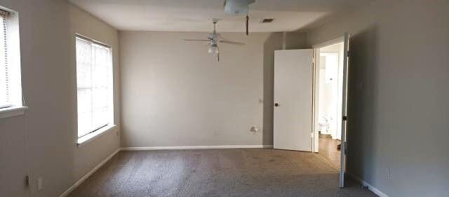 empty room with a healthy amount of sunlight, ceiling fan, and baseboards