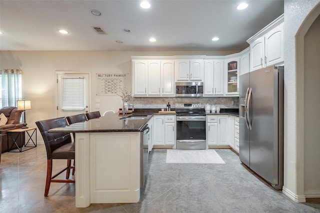 kitchen with visible vents, a breakfast bar area, a peninsula, stainless steel appliances, and a sink