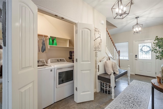 washroom featuring a chandelier, laundry area, dark tile patterned floors, baseboards, and washing machine and clothes dryer