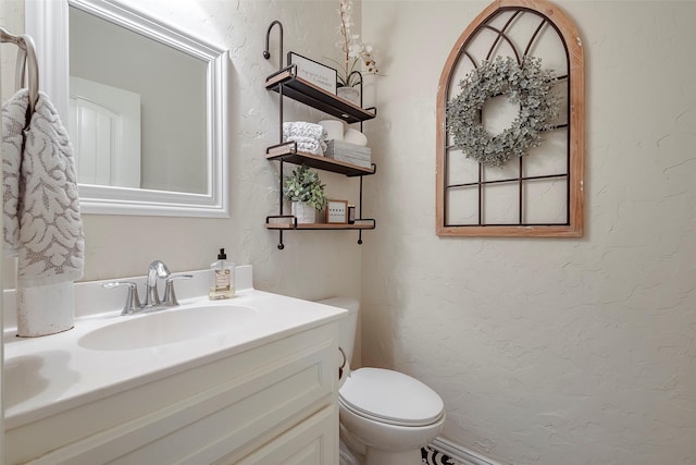 bathroom featuring toilet, vanity, and a textured wall