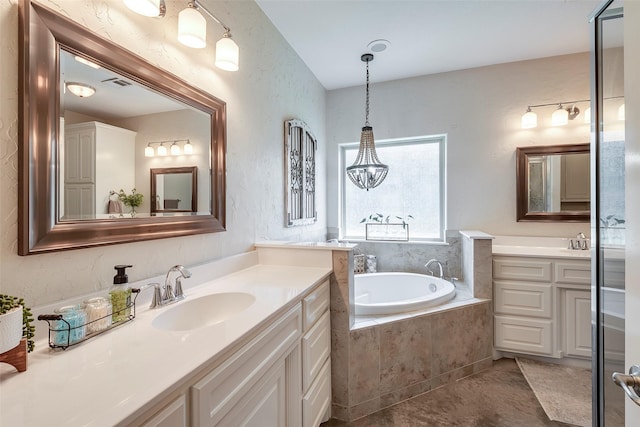 full bathroom with a textured wall, a sink, a garden tub, tile patterned flooring, and two vanities