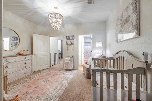 bedroom with a notable chandelier, light colored carpet, visible vents, a crib, and baseboards