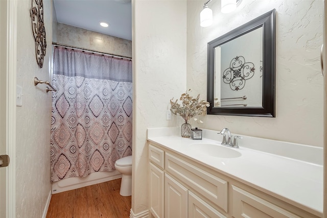 bathroom featuring a textured wall, toilet, shower / tub combo, vanity, and wood finished floors