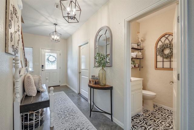 interior space featuring dark tile patterned floors, baseboards, and a chandelier