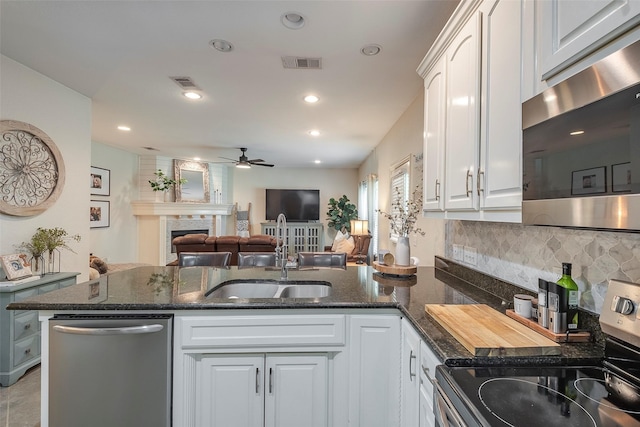 kitchen with visible vents, a tiled fireplace, appliances with stainless steel finishes, a sink, and a peninsula