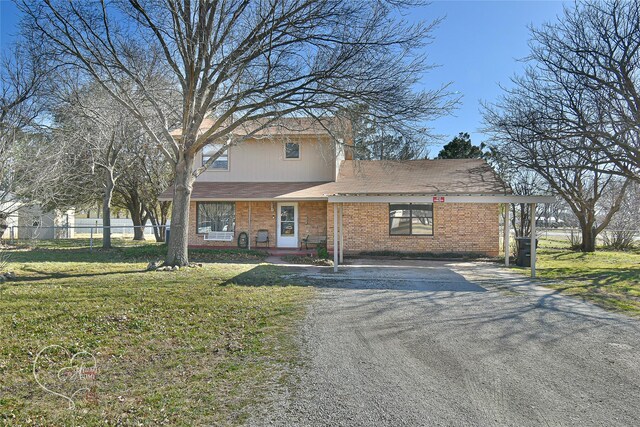 traditional home featuring a front yard, brick siding, fence, and driveway