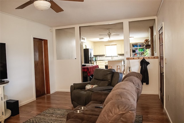 living room with dark wood-type flooring, baseboards, and a ceiling fan