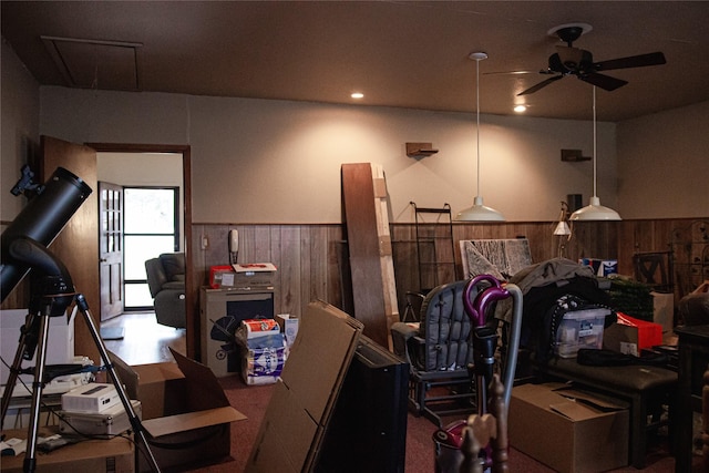 interior space featuring wood walls, wainscoting, and a ceiling fan