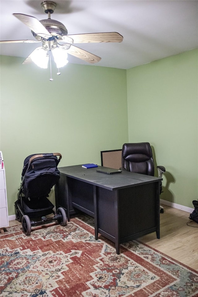 office featuring wood finished floors, a ceiling fan, and baseboards