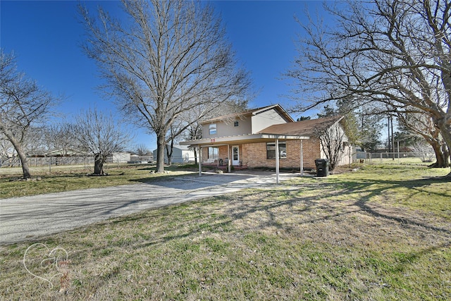 view of front of property with driveway, brick siding, a front lawn, and fence