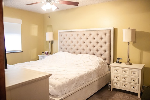 bedroom featuring a ceiling fan, dark carpet, and a textured ceiling