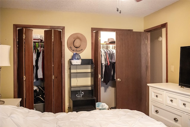 bedroom with a textured ceiling, a walk in closet, and multiple closets