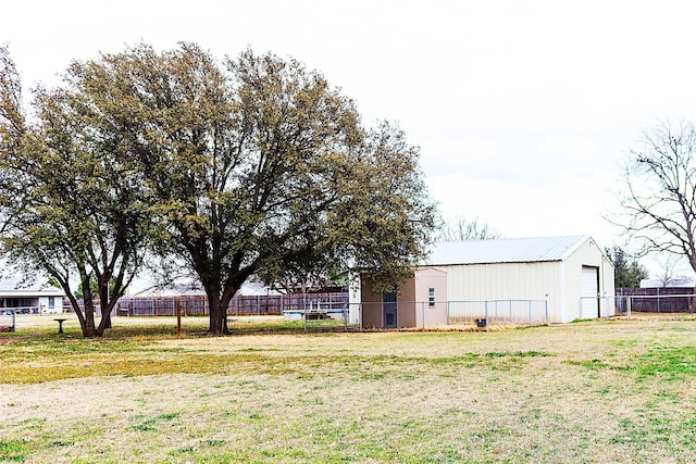 view of yard featuring a pole building, an outdoor structure, fence, and a detached garage