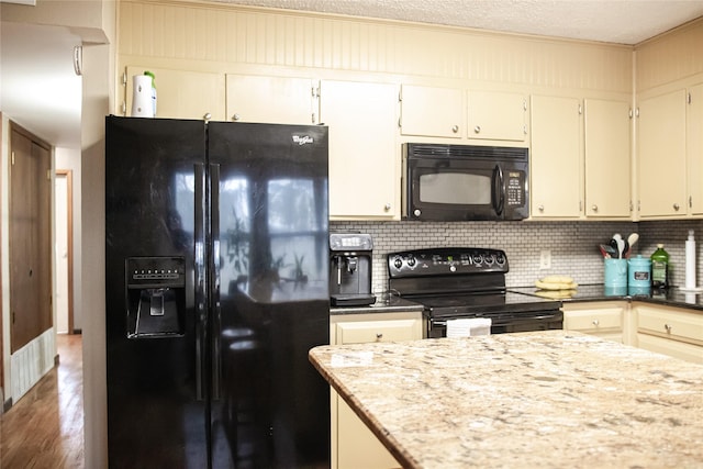 kitchen with decorative backsplash, light stone counters, wood finished floors, a textured ceiling, and black appliances