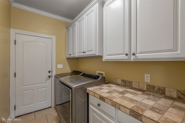 clothes washing area with cabinet space, light tile patterned floors, crown molding, and washing machine and clothes dryer