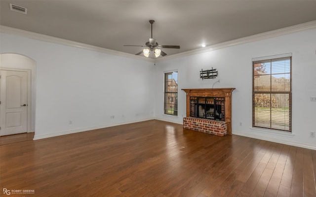 unfurnished living room featuring dark wood-type flooring, a brick fireplace, visible vents, and crown molding