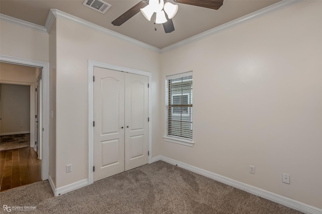 unfurnished bedroom with ornamental molding, a closet, visible vents, and carpet flooring