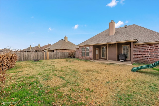 back of house with a yard, brick siding, a patio, and a fenced backyard