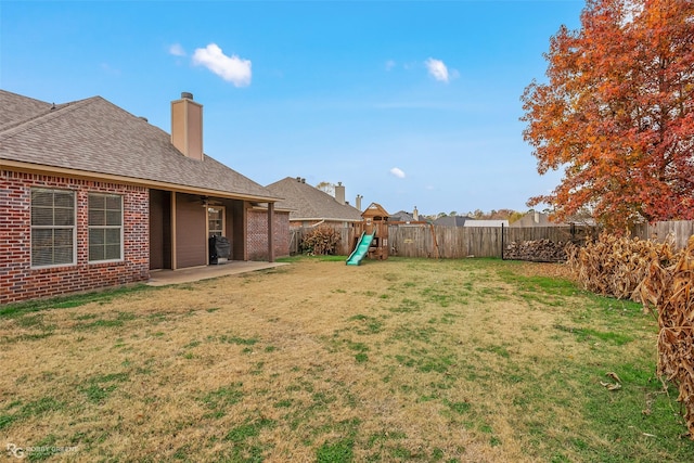 view of yard with a ceiling fan, a patio area, a fenced backyard, and a playground