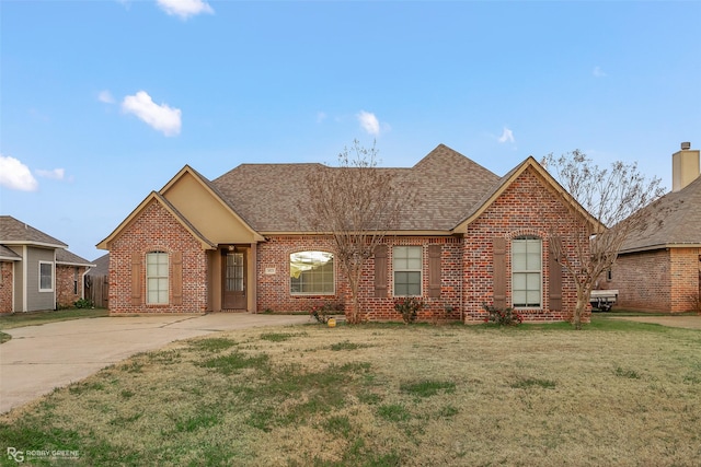 ranch-style house featuring brick siding, roof with shingles, and a front lawn