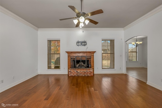 unfurnished living room featuring ornamental molding, arched walkways, wood-type flooring, and a fireplace