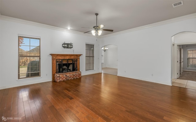 unfurnished living room with arched walkways, hardwood / wood-style flooring, a fireplace, and visible vents