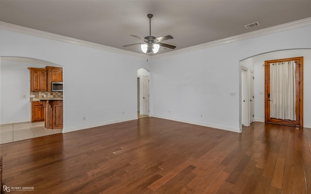 unfurnished living room with arched walkways, visible vents, and wood finished floors