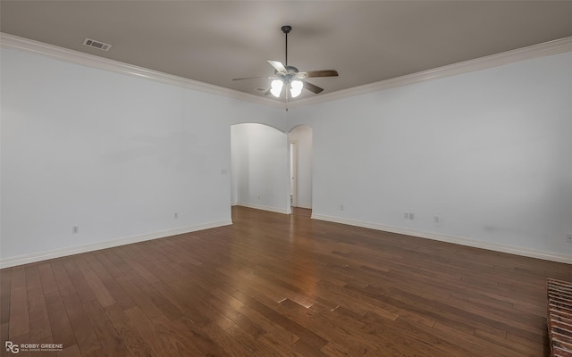 spare room featuring visible vents, arched walkways, a ceiling fan, dark wood-style floors, and crown molding