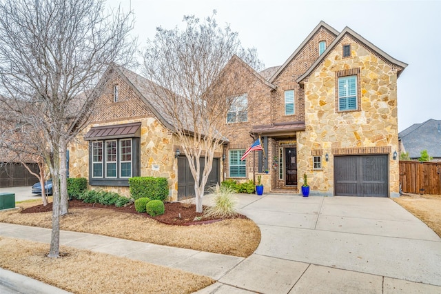 view of front of house featuring an attached garage, stone siding, driveway, and fence