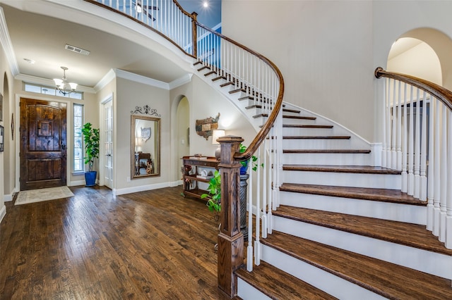 foyer with visible vents, a towering ceiling, hardwood / wood-style floors, ornamental molding, and baseboards